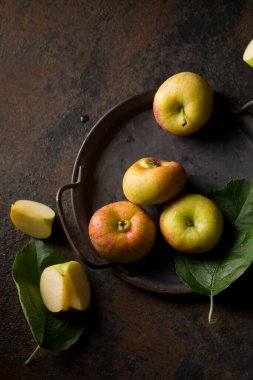 Small flattened apples on a metal tray on a dark background