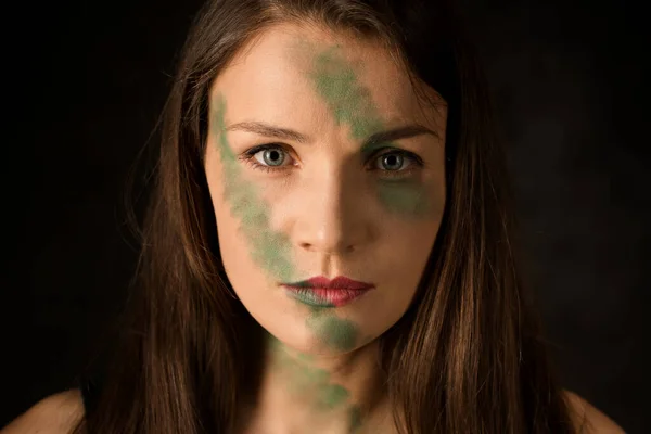 Woman warrior with camouflage makeup on a dark background