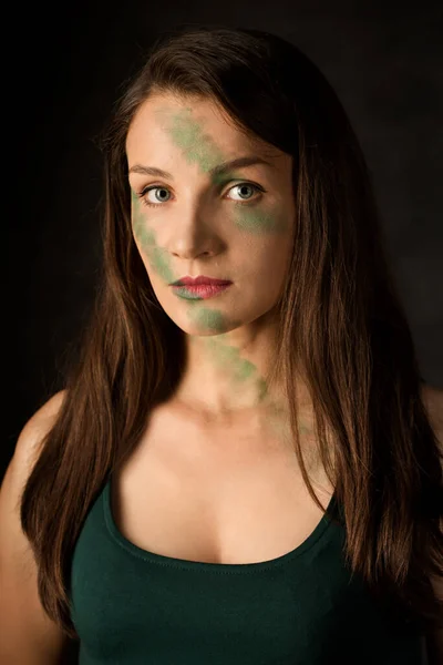 Woman warrior with camouflage makeup on a dark background