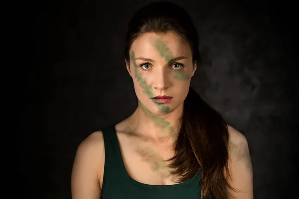 Woman warrior with camouflage makeup on a dark background