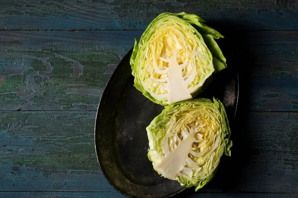 Young early cabbage cut in half on a dark background