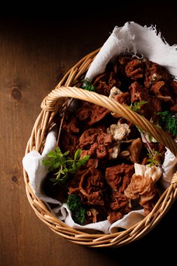 Forest morel mushrooms in a wicker basket on a wooden background