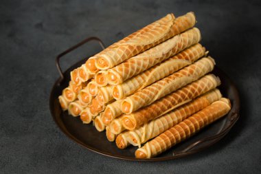 Ruddy crispy tubes with condensed milk on a metal tray