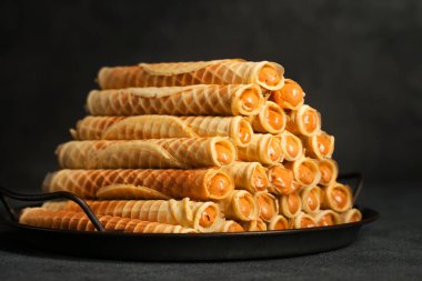 Ruddy crispy tubes with condensed milk on a metal tray