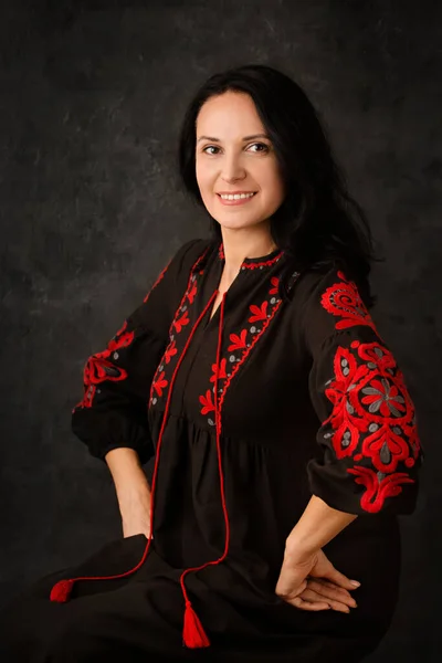美しいですウクライナの女性で黒のドレスに赤い刺繍で暗い背景 — ストック写真