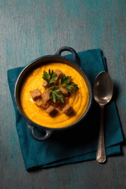 Kızarmış soğanlı kabak püresi, kraker ve mavi arka planda mavi bir kasede maydanoz.