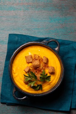 Kızarmış soğanlı kabak püresi, kraker ve mavi arka planda mavi bir kasede maydanoz.