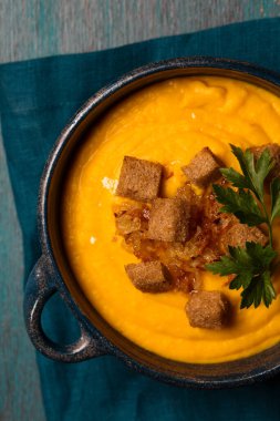 Kızarmış soğanlı kabak püresi, kraker ve mavi arka planda mavi bir kasede maydanoz.