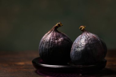 Tahta bir arka planda küçük bir tabakta iki sulu incir.