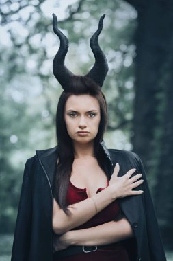 Ormanda uzun siyah boynuzları olan güzel bir kadın. Cadılar Bayramı konsepti