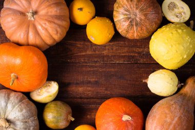 Tahta arka planda farklı türde küçük olgun balkabakları.