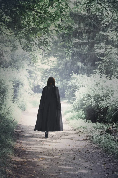 Μια Γυναίκα Μαύρη Κάπα Διασχίζει Ένα Σκοτεινό Τρομακτικό Δάσος Απόκριες — Φωτογραφία Αρχείου