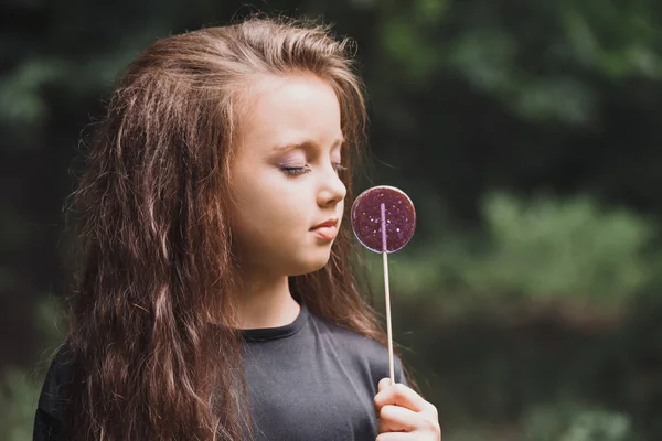 一个穿着黑色衣服 手上拿着紫色糖果的可爱女孩 — 图库照片