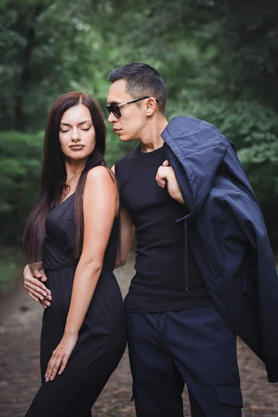 森の中の暗い服を着た若い美しいカップルの肖像画 — ストック写真