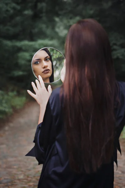 美しい若い女性が鏡を見ている ハロウィンのコンセプト — ストック写真