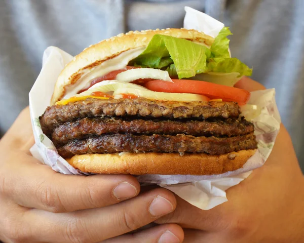 Manos sosteniendo gran sabor Hamburguesa con queso — Foto de Stock