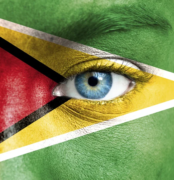 Human face painted with flag of Guyana — Stock Photo, Image