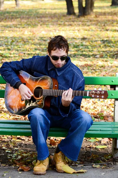 Homme jouant de la guitare sur banc — Photo