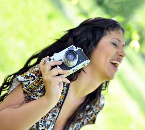 Mujer sonriente sosteniendo la cámara vintage — Foto de Stock