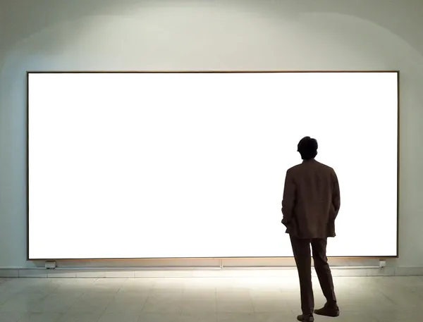 Hombre en la sala de la galería mirando marcos vacíos —  Fotos de Stock