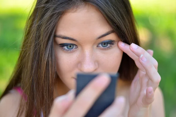 Beautiful girl checking her makeup outdoor — Stock Photo, Image