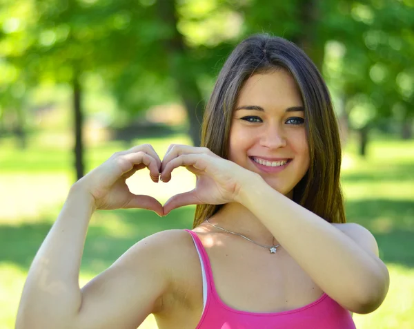 Leuke tiener meisje waardoor hart vorm met haar handen buitenshuis — Stockfoto