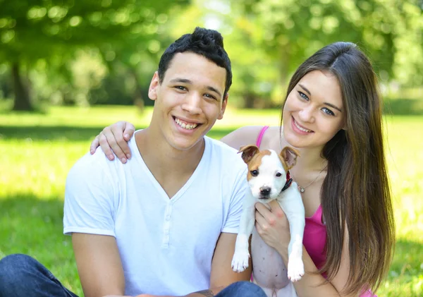 Счастливая пара с щенком в парке — стоковое фото