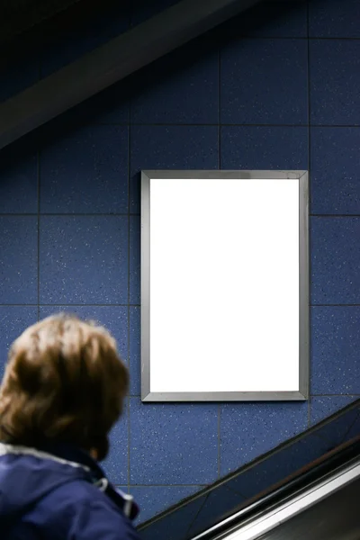 Man looking at blank billboard while climbing on escalator stair — Stock Photo, Image