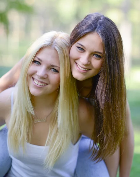 Close up portrait of two happy girls hugging outdoors — Stock Photo, Image