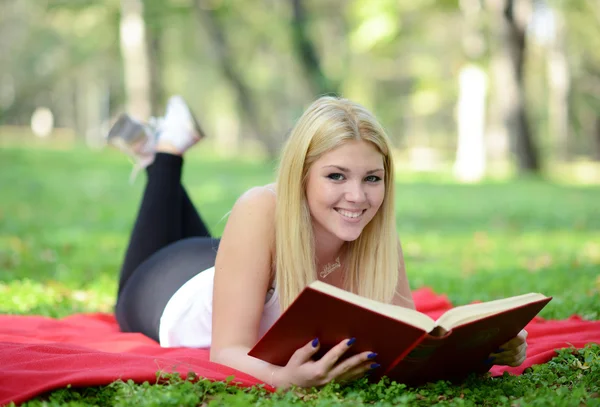 Bella donna sorridente leggere libro nel parco — Foto Stock