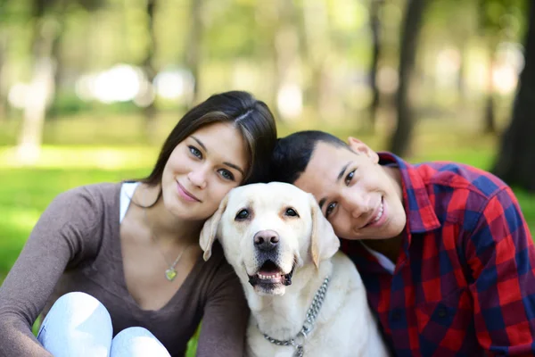 Happy couple with puppy dog at park — Stock Photo, Image