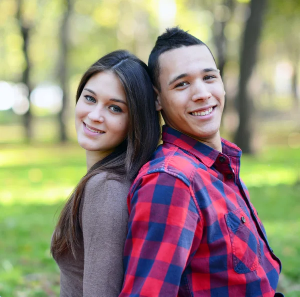 Happy young couple back to back in park — Stock Photo, Image