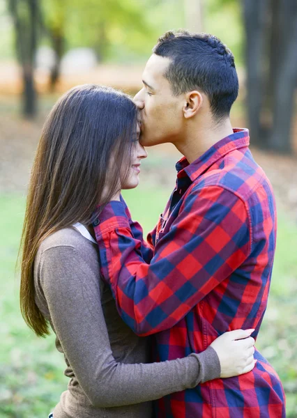 Close up of boy kissing girlfriend on forehead outdoor — Stock Photo, Image