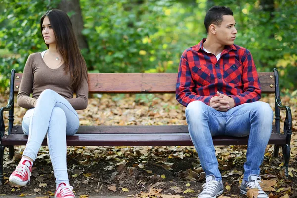 Jovem casal em briga sentado no banco no parque — Fotografia de Stock