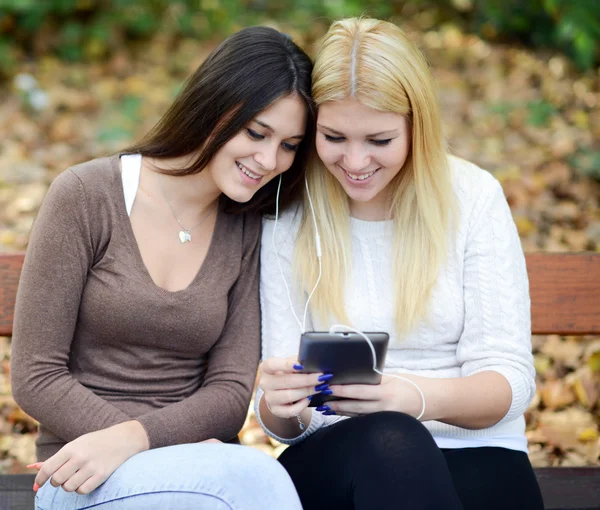 Dos mujeres jóvenes mirando tableta y chating en línea con un amigo — Foto de Stock