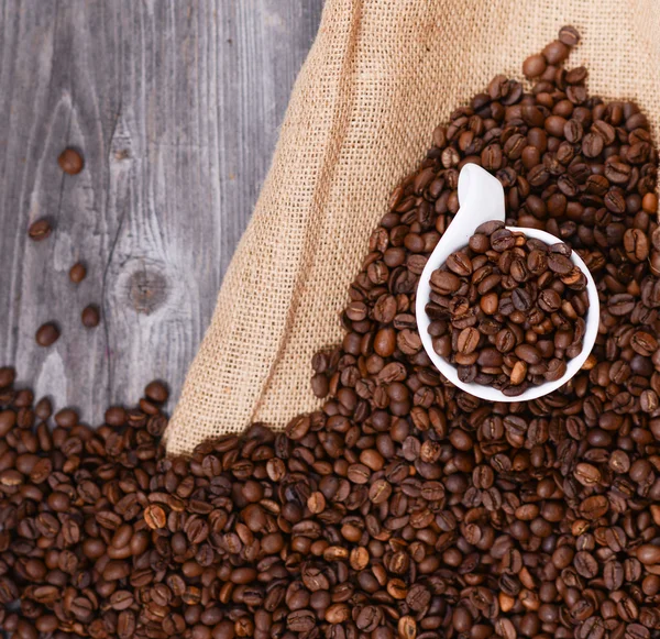 Cup of coffee filled with coffee beans against wooden background — Stock Photo, Image