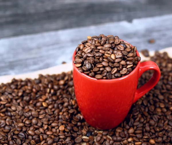 Copa de café lleno de granos de café sobre fondo de madera — Foto de Stock