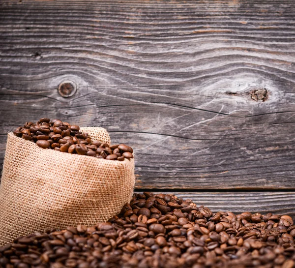 Sack of coffee beans on wood background — Stock Photo, Image