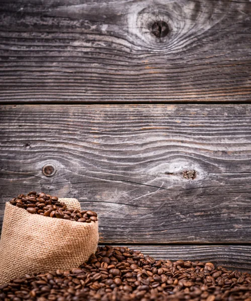 Sack of coffee grains against wooden background — Stock Photo, Image