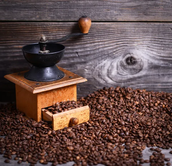 Manual coffee grinder with beans on wooden background — Stock Photo, Image