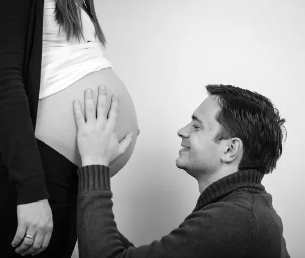 Nahaufnahme eines Mannes, der den Bauch seiner schönen schwangeren Frau küsst — Stockfoto