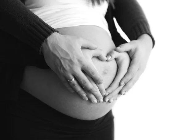 Casal grávida com as mãos ao redor da barriga fazendo uma forma de coração — Fotografia de Stock