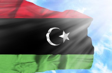 Mavi gökyüzü ile yapraklara karşı bayrak sallayarak libya