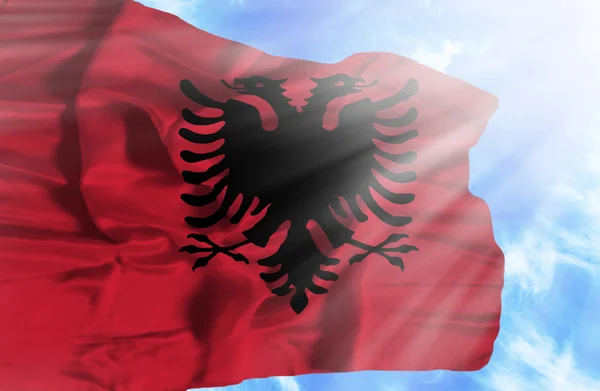 Albania vifter med flagg mot blå himmel med solstråler – stockfoto