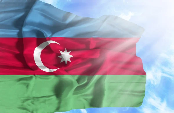 Azerbeidzjan zwaaien vlag tegen blauwe hemel met zonnestralen — Stockfoto