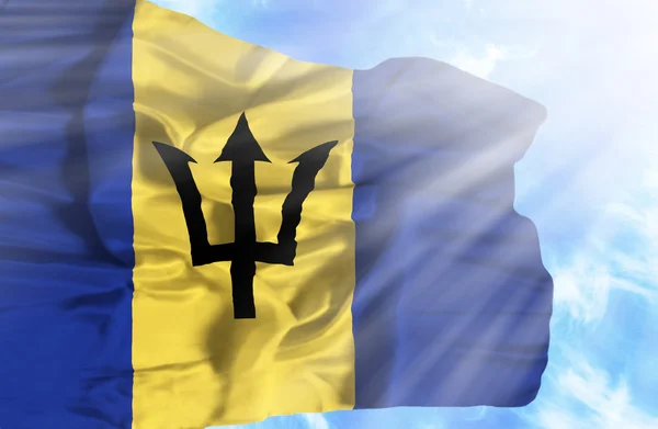 Barbados heiluttaa lippua sinistä taivasta vasten auringonsäteillä — kuvapankkivalokuva