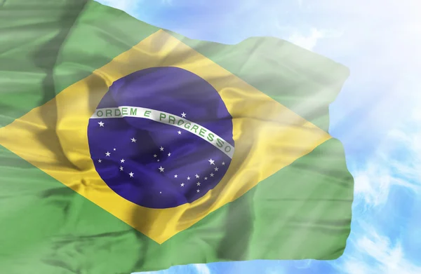 Brazil waving flag against blue sky with sunrays — Stock Photo, Image