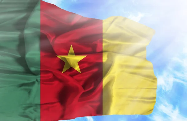 Kameroen zwaaien vlag tegen blauwe hemel met zonnestralen — Stockfoto
