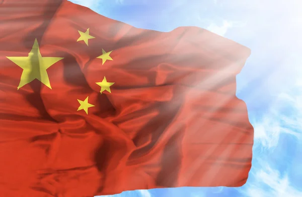 Chine agitant drapeau contre ciel bleu avec des rayons de soleil — Photo