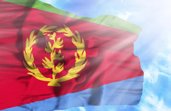 Eritrea waving flag against blue sky with sunrays — Stock Photo, Image